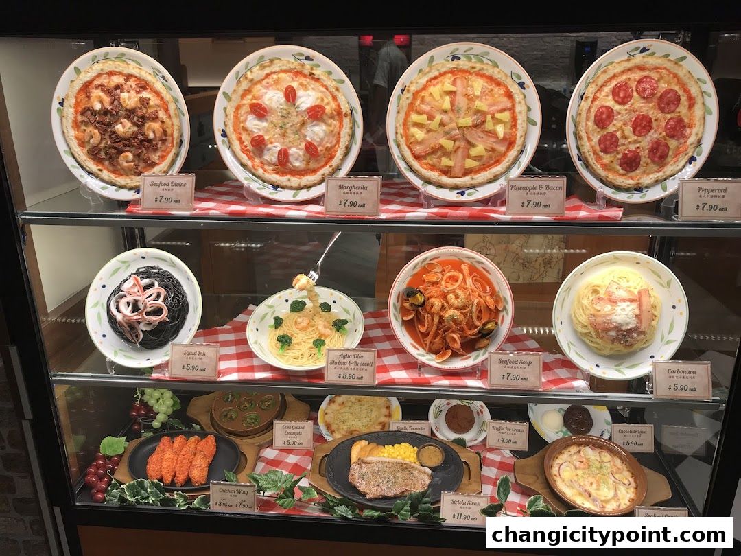 A display case showcasing realistic food models of pizzas, pastas, and other dishes with prices.