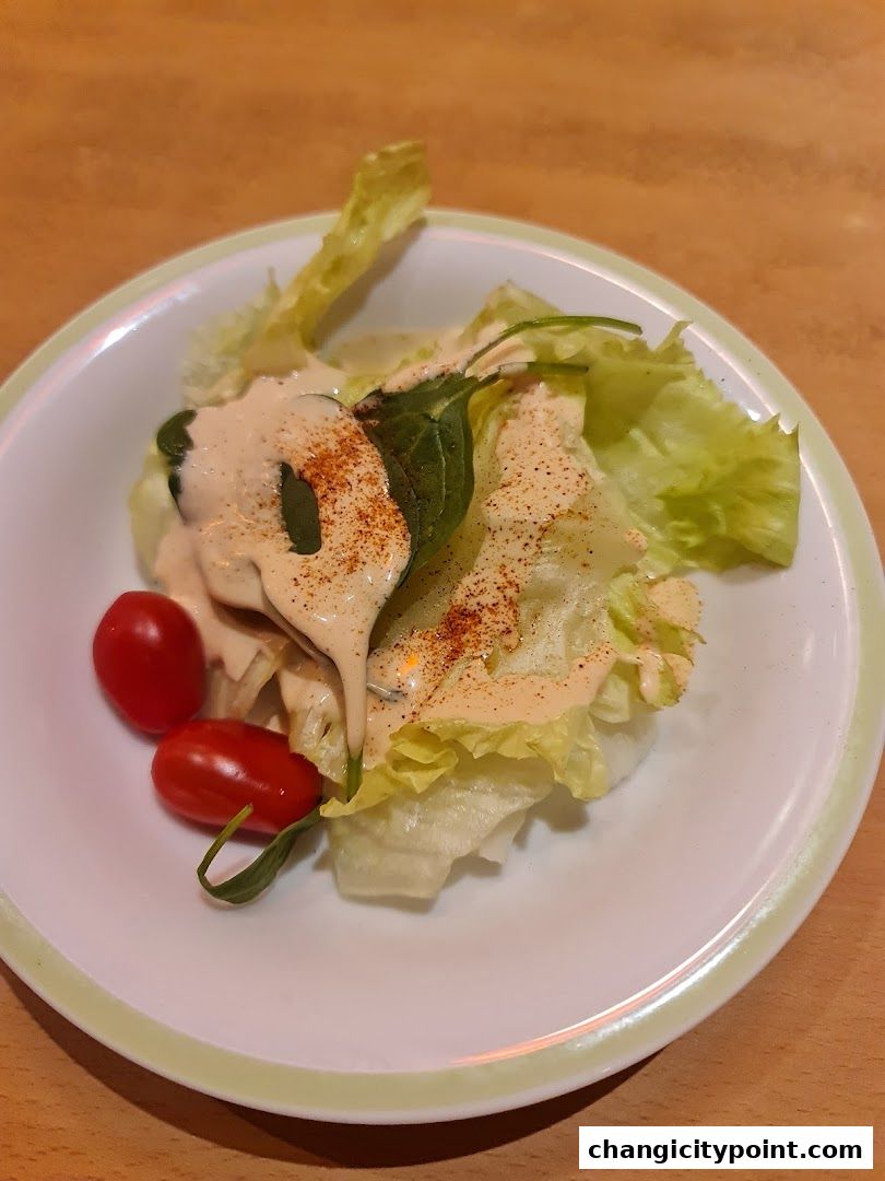 A refreshing salad with lettuce, cherry tomatoes, and creamy dressing, sprinkled with paprika.