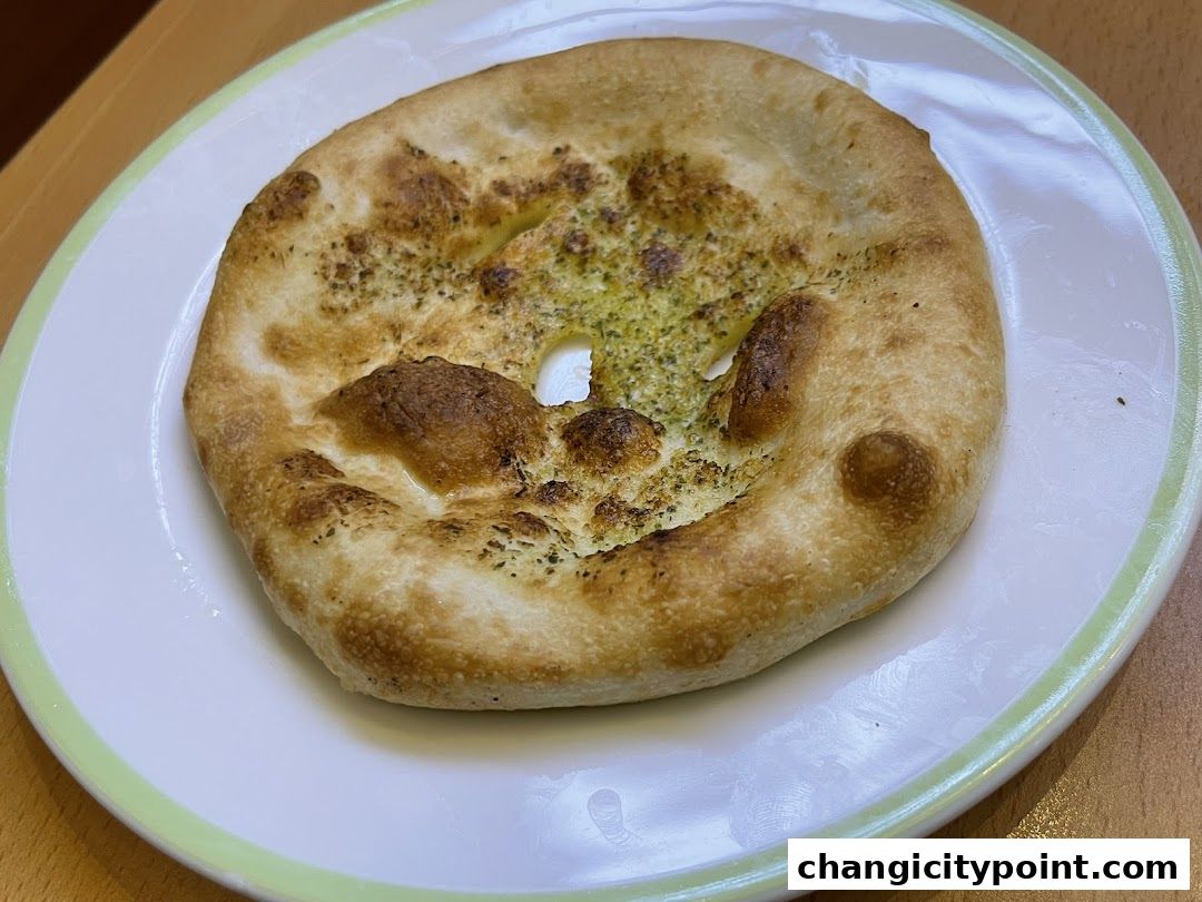 A close-up shot of a golden-brown garlic bread on a white plate.