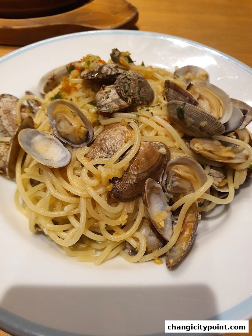 A plate of spaghetti with clams, garnished with herbs and garlic.