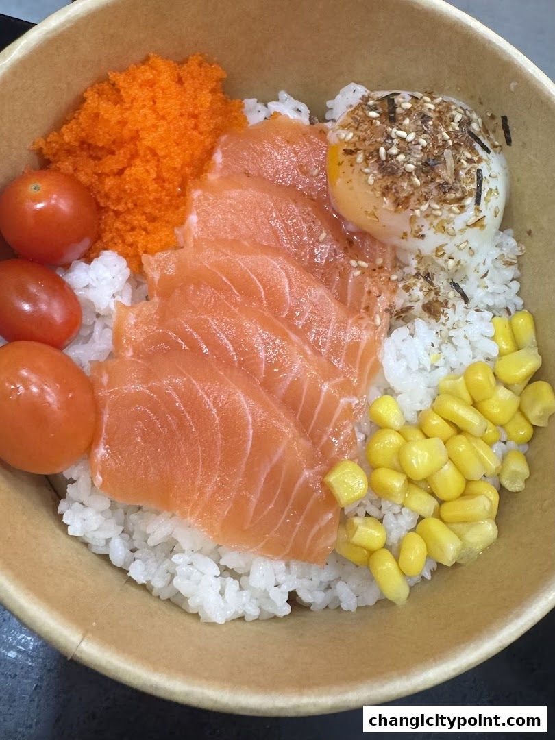 A bowl of rice topped with fresh salmon, egg, corn, cherry tomatoes, and fish roe.