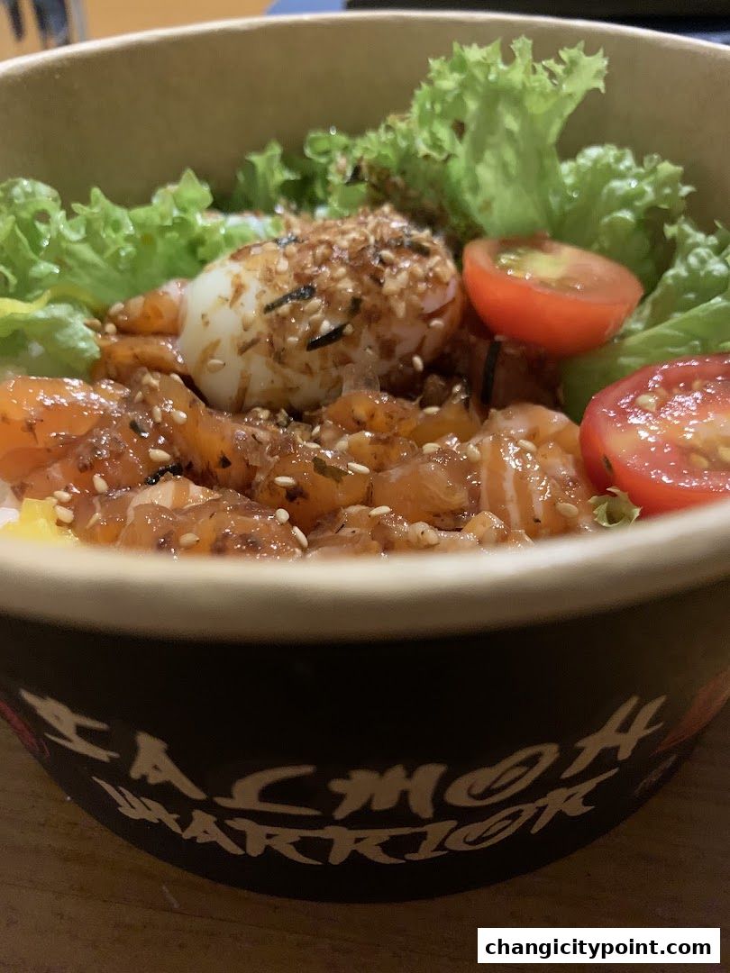 A close-up of a salmon bowl with egg, lettuce, and tomatoes.