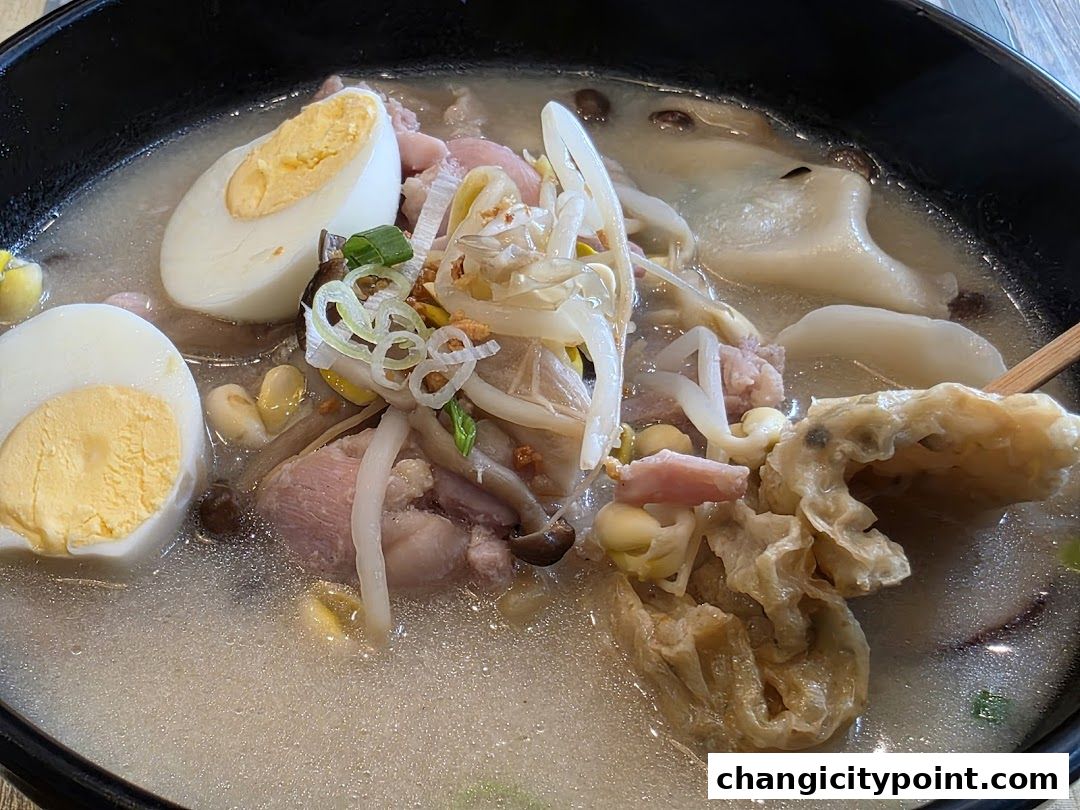 A close-up of a steaming bowl of hot pot with eggs, meat, and vegetables.