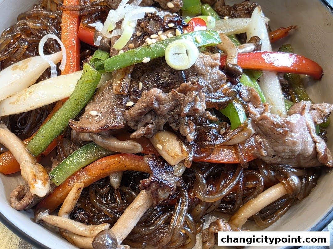 A close-up of a delicious Korean Japchae dish with beef, vegetables, and noodles.
