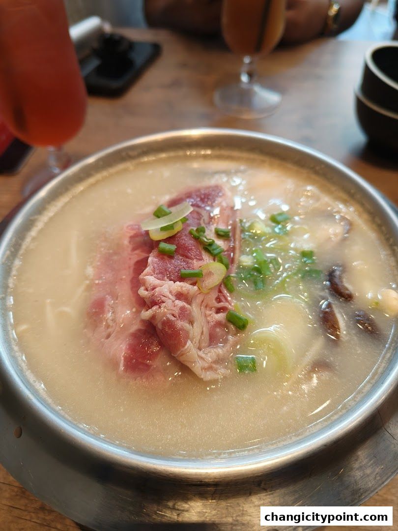 A close-up of a steaming hot pot dish with meat and vegetables.