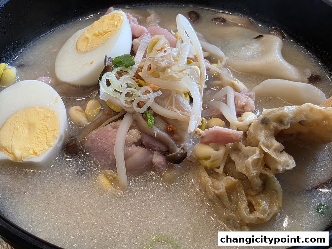 A close-up of a steaming bowl of hot pot with eggs, meat, and vegetables.