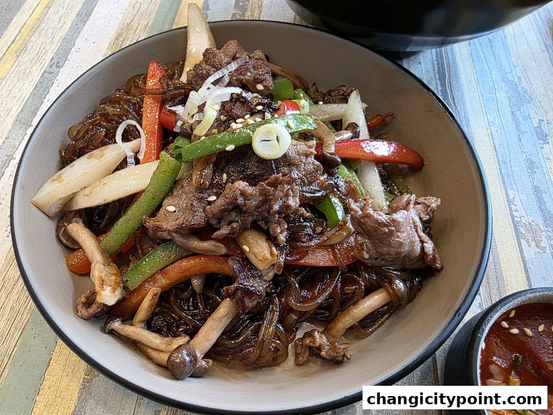 A close-up of a delicious Korean stir-fried glass noodle dish with beef and vegetables.