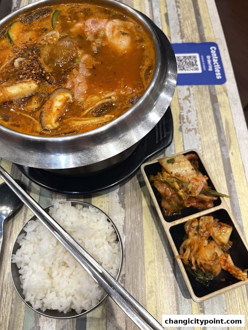 A steaming pot of hot pot with rice and kimchi, ready to be enjoyed.