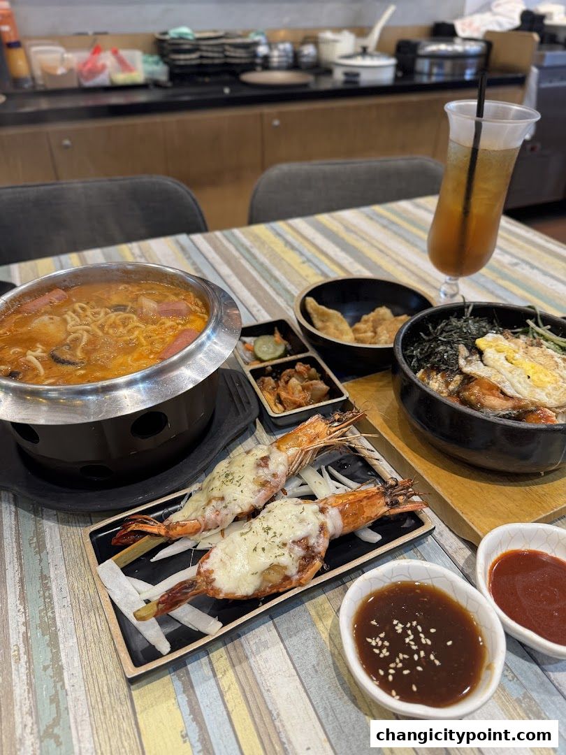 A table laden with Korean dishes including hot pot, grilled cheese shrimp, and bibimbap.