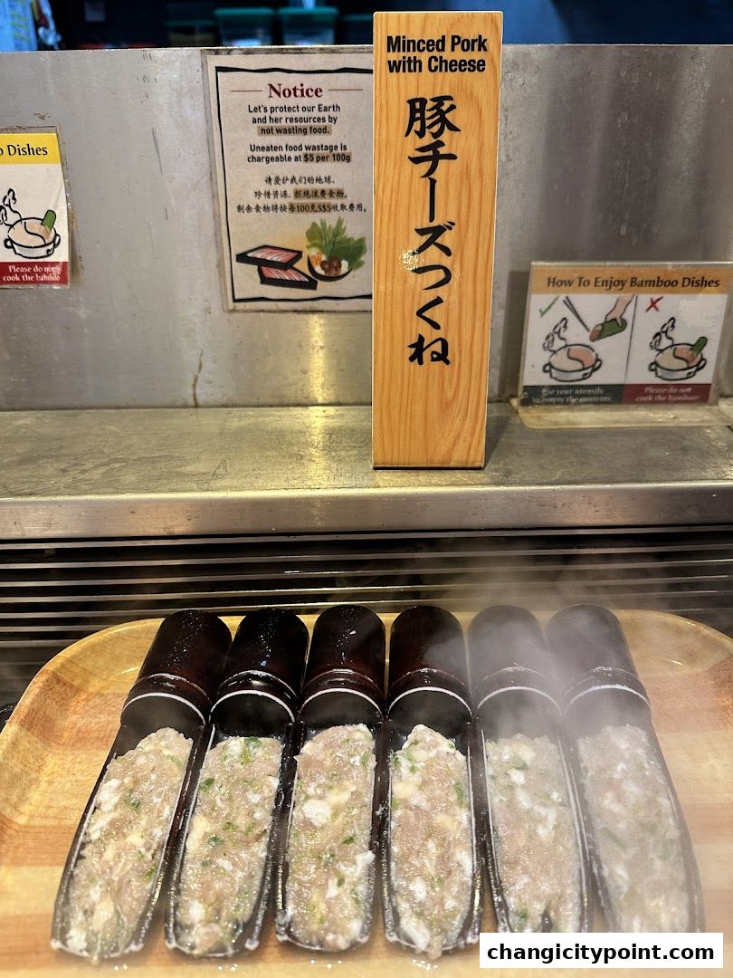 A wooden sign displays 'Minced Pork with Cheese' above a tray of raw food in bamboo-shaped containers.