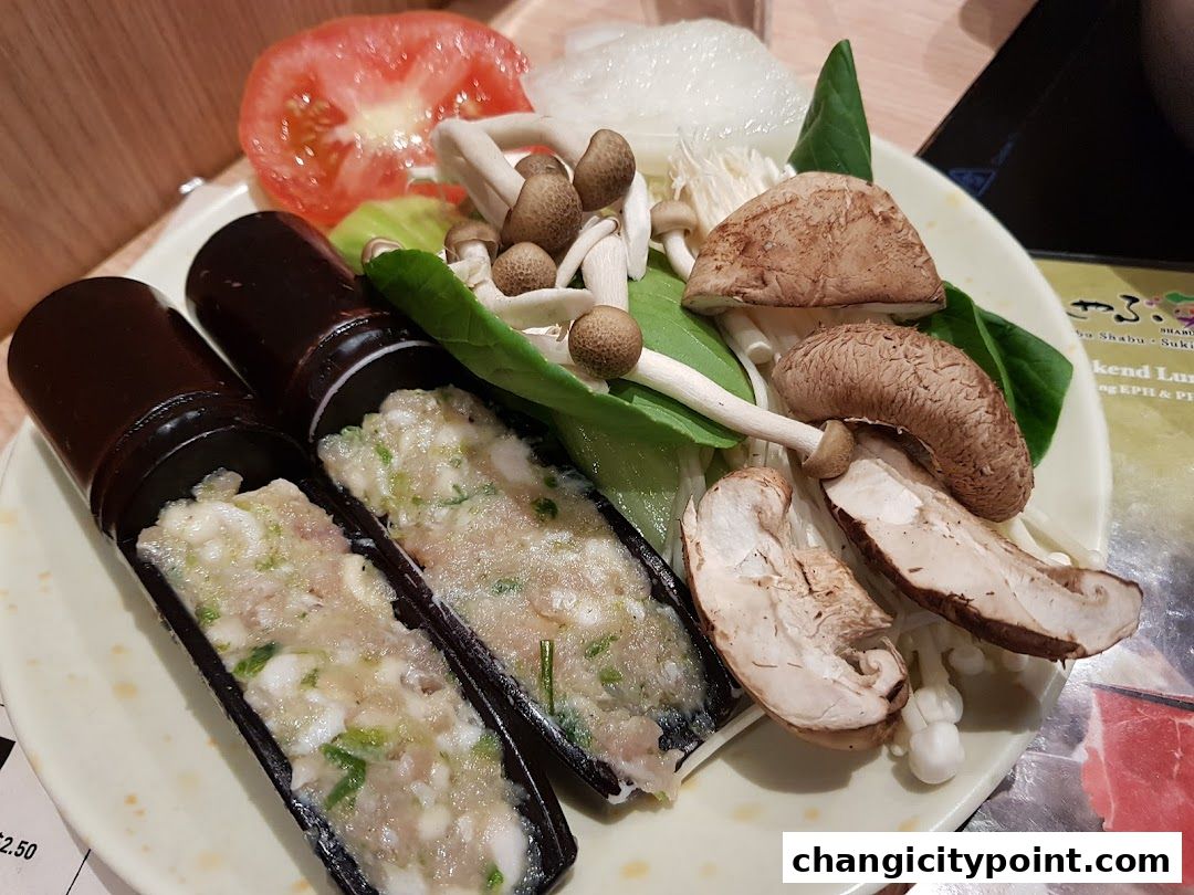 A plate of fresh vegetables and minced meat served in bamboo tubes for shabu-shabu.