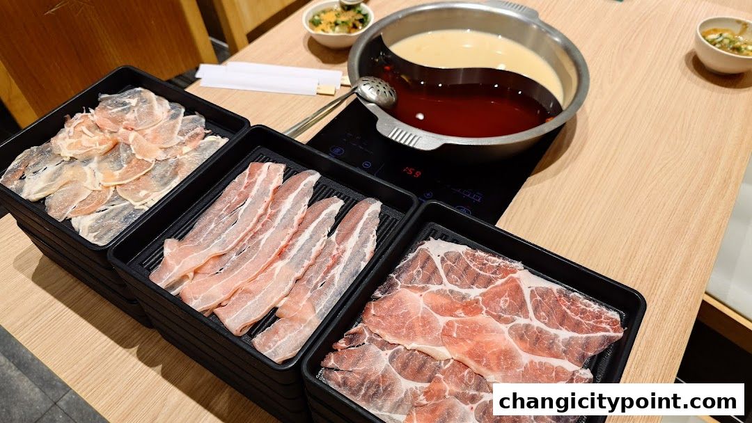 A table set for shabu-shabu with thinly sliced meats and a dual-broth pot.