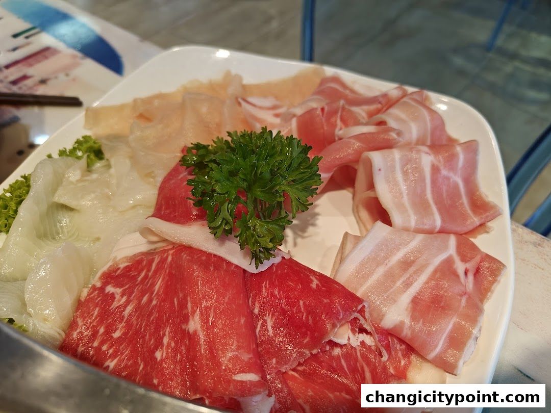 A platter of thinly sliced raw meats and vegetables for hot pot.