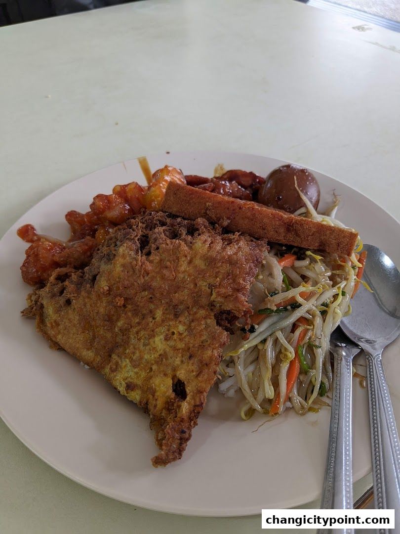 A plate of rice with various toppings including fried egg, stir-fried vegetables, and braised egg.