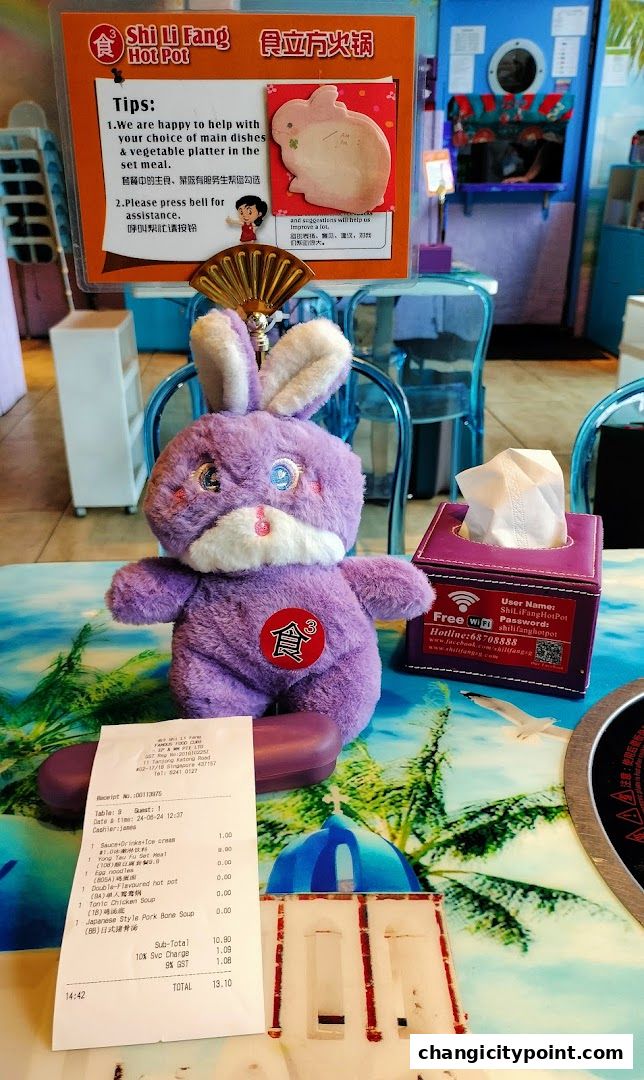 A purple plush bunny sits on a table with a receipt and a tissue box.