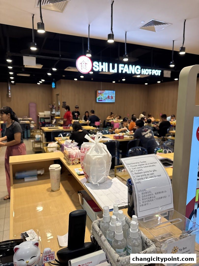 Interior of Shi Li Fang Hot Pot restaurant with diners and a counter.
