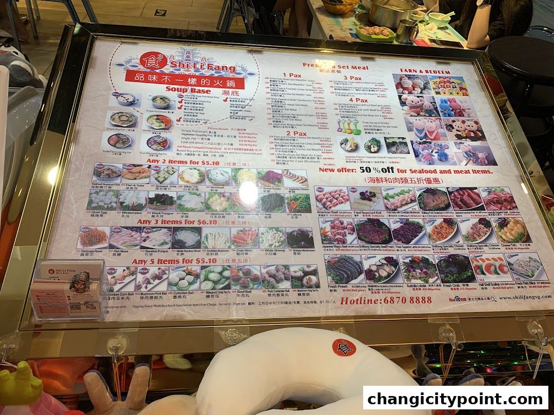 A menu board for Shi Li Fang Hot Pot featuring soup bases, set meals, and a variety of hot pot ingredients.