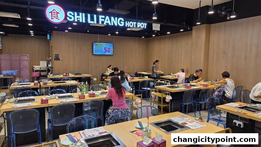 Interior of Shi Li Fang Hot Pot restaurant with diners and hot pot stations.