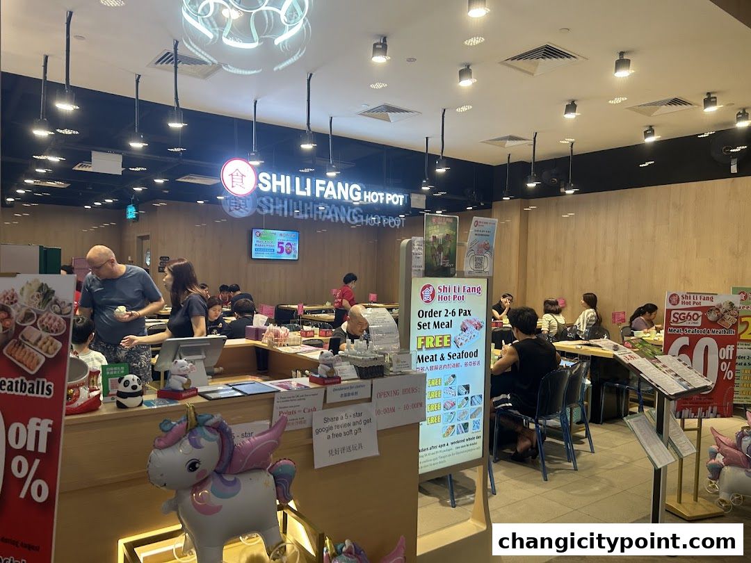 Interior view of Shi Li Fang Hot Pot restaurant with diners and promotional posters.
