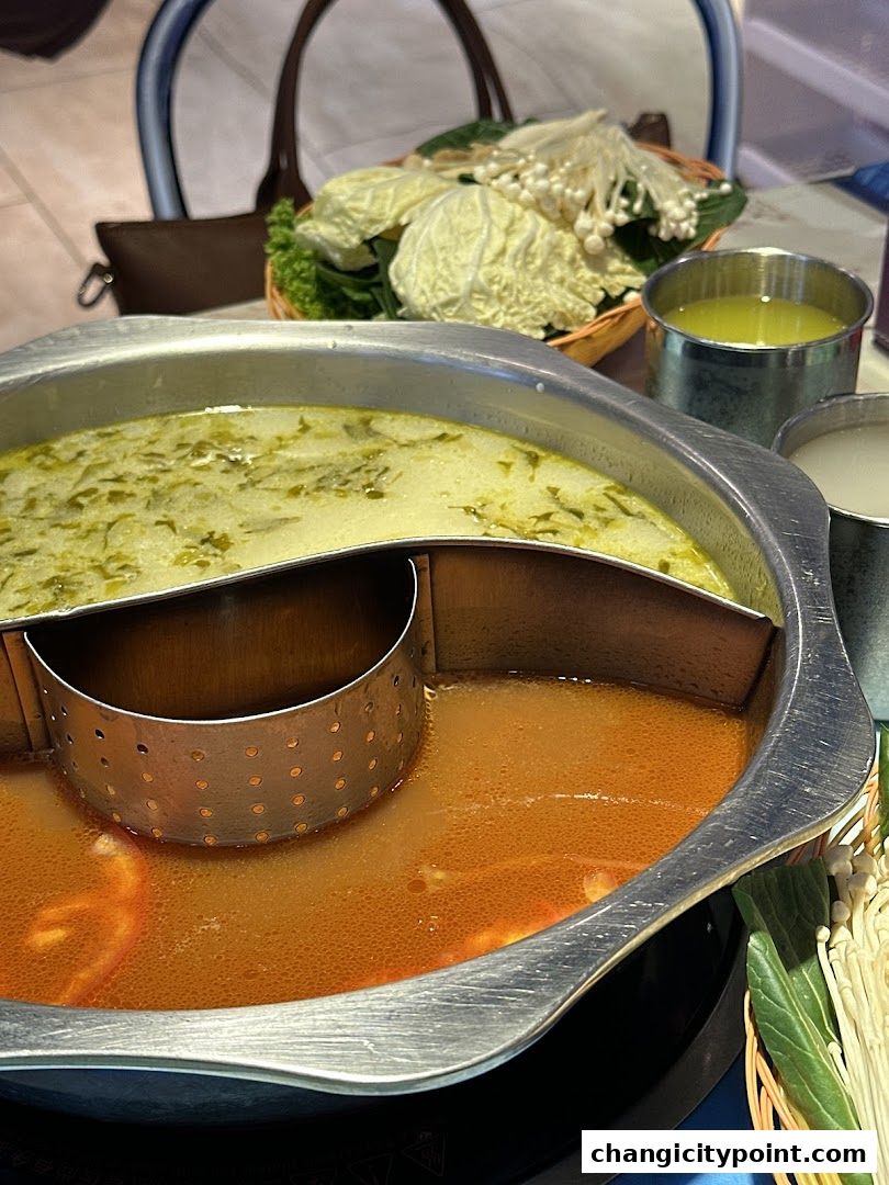 A split hot pot with two broths, vegetables, and enoki mushrooms.
