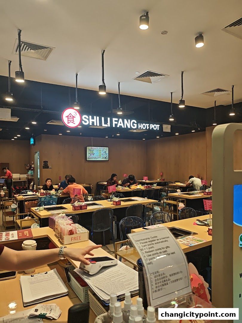 Interior of Shi Li Fang Hot Pot restaurant with diners and staff.
