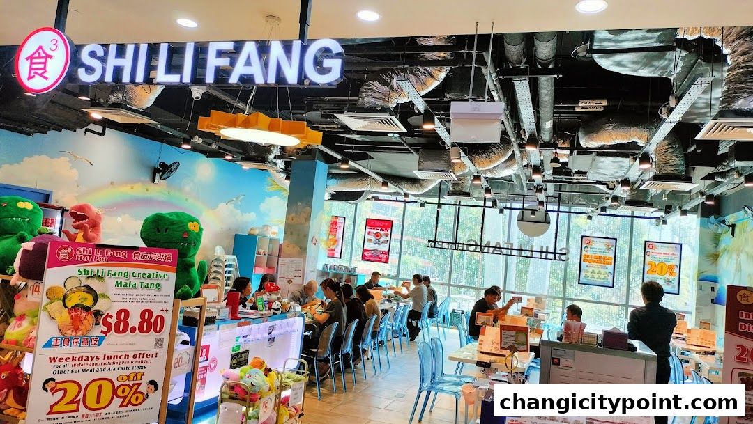 Interior of Shi Li Fang Hot Pot restaurant with diners and promotional posters.