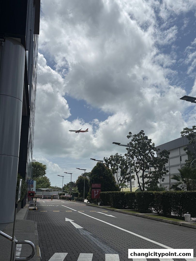 An airplane flies over a street with a Singtel store visible.