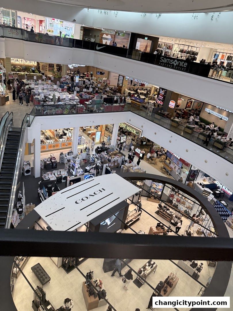 A multi-level shopping mall interior with various stores and escalators.