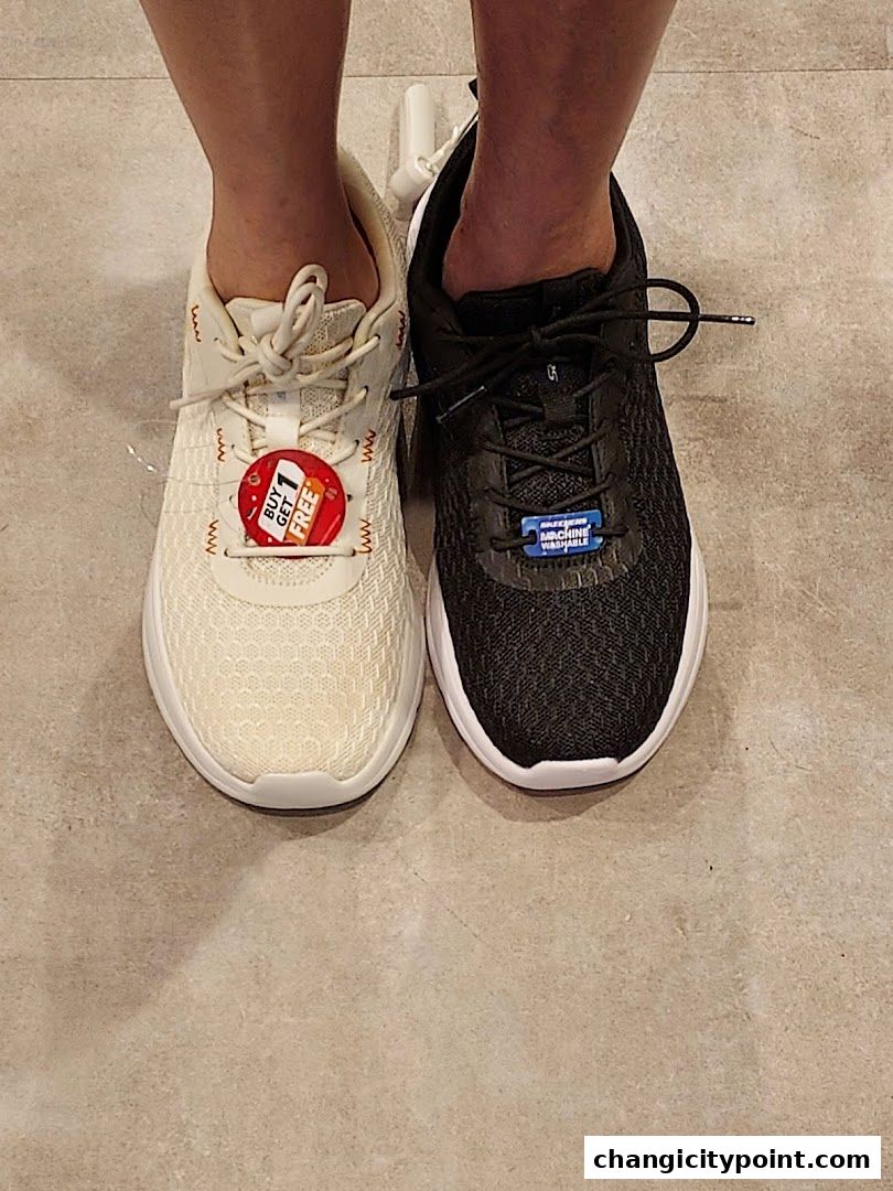 A close-up of two pairs of Skechers shoes, one cream and one black, with a 'Buy 1 Get 1 Free' tag.