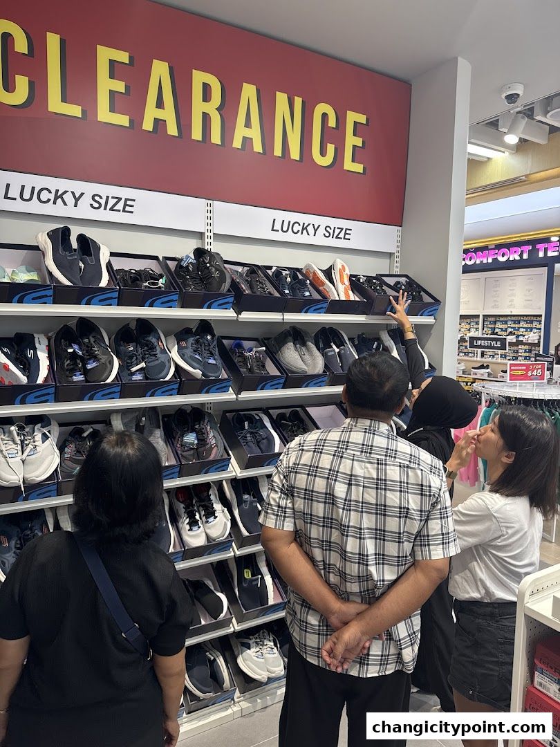 Shoppers browse shoes on display under a large 'CLEARANCE' sign at Skechers.