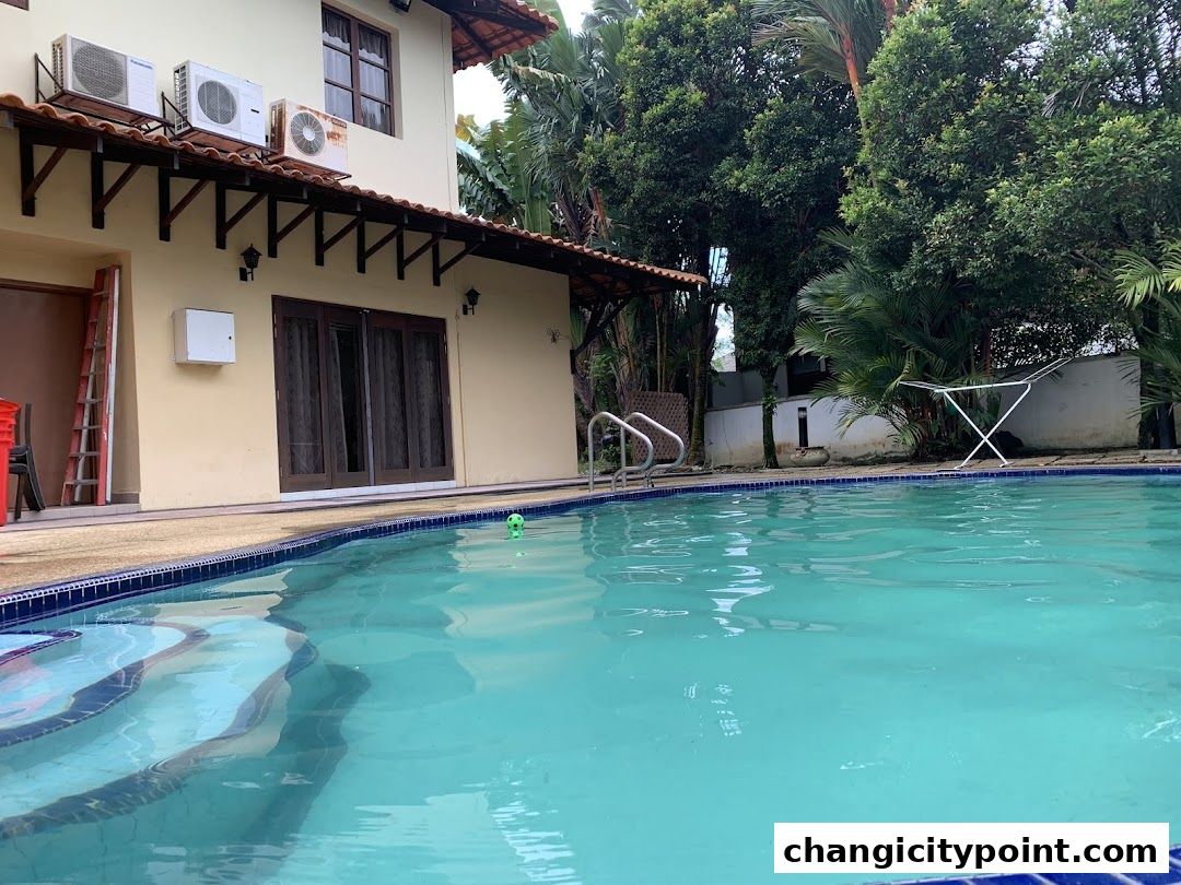 A swimming pool with steps and a building with air conditioners in the background.