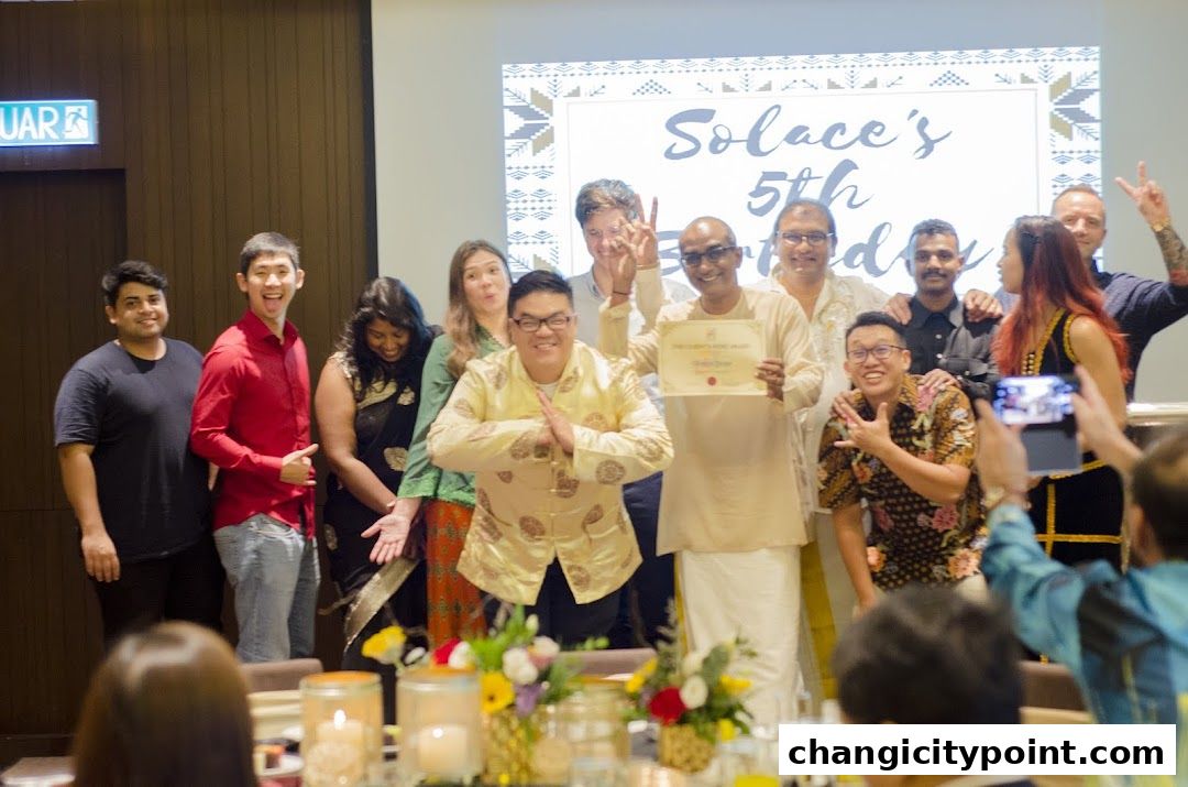 A group of people celebrating Solace Asia's 5th birthday with a certificate presentation.