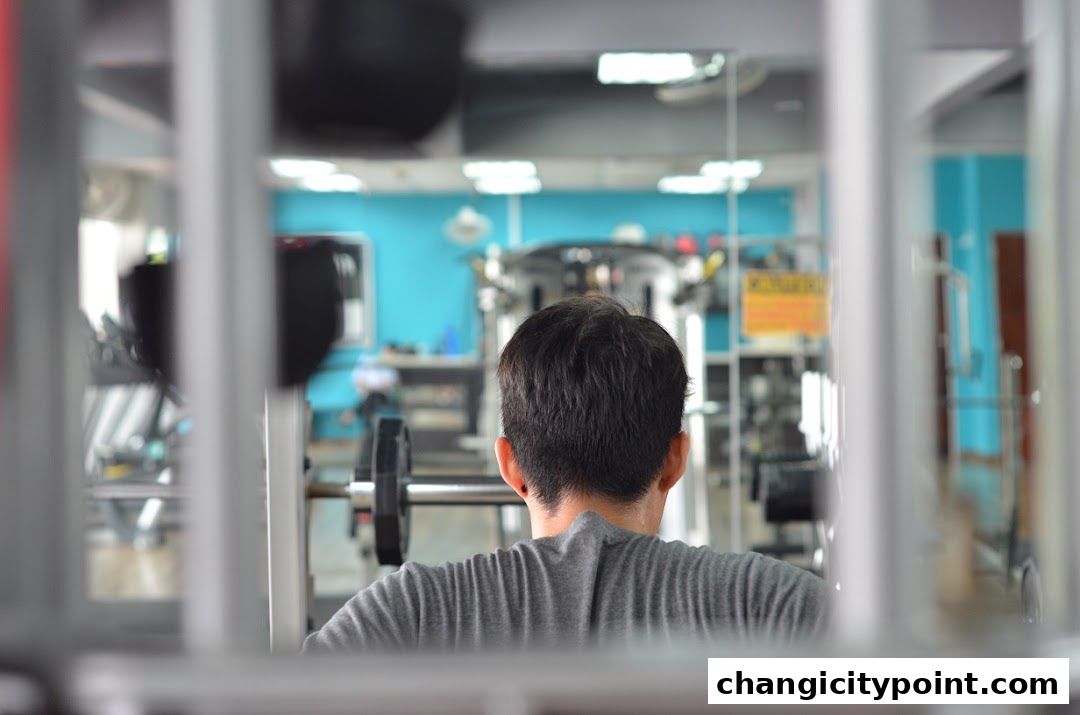 Man working out at a gym with weightlifting equipment in the background.