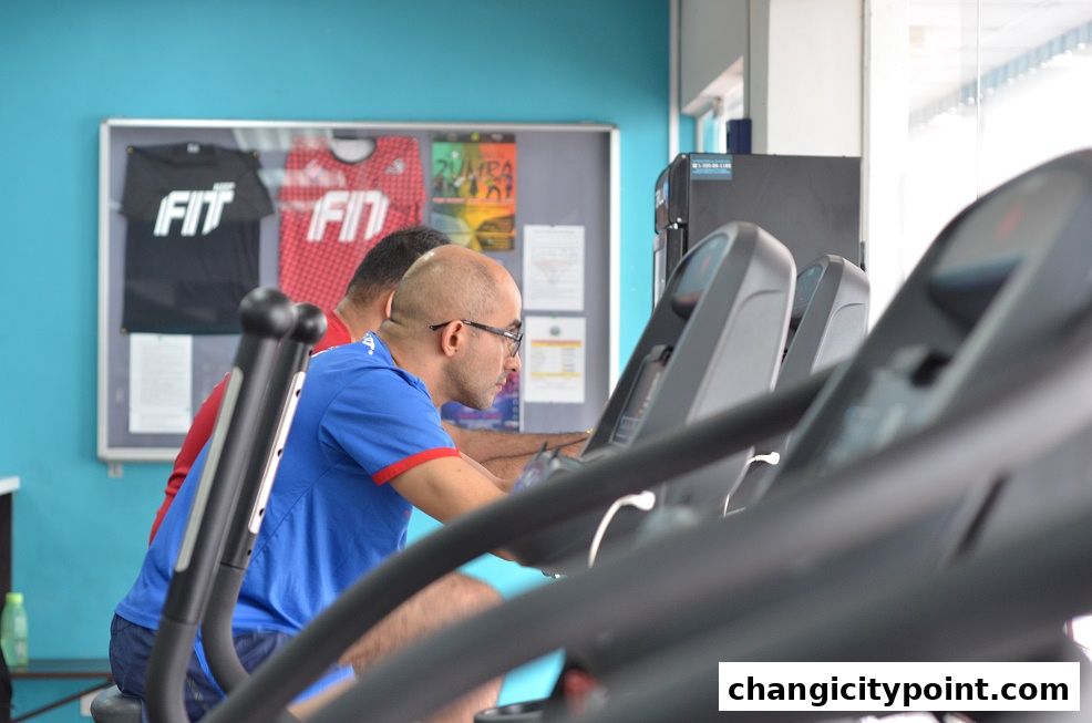 Two men exercising on treadmills in a gym with fitness-related posters on the wall.