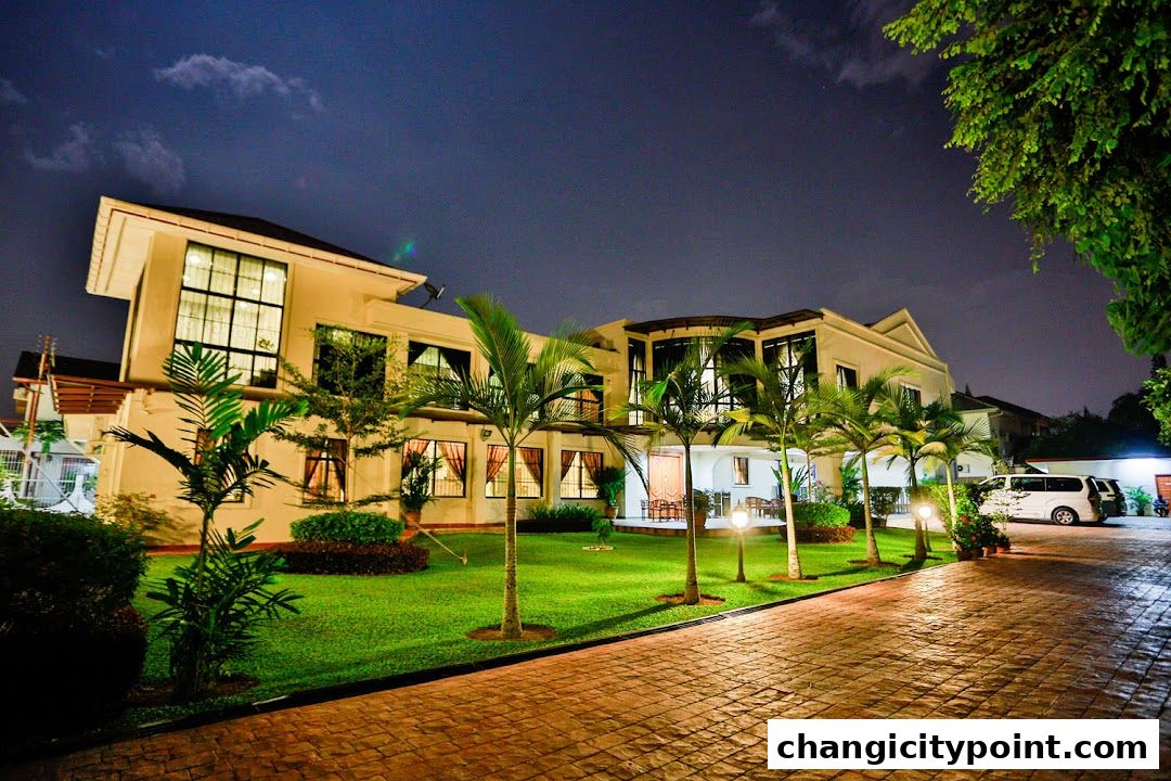 Exterior of Solace Asia Singapore at night, with manicured lawn and palm trees.
