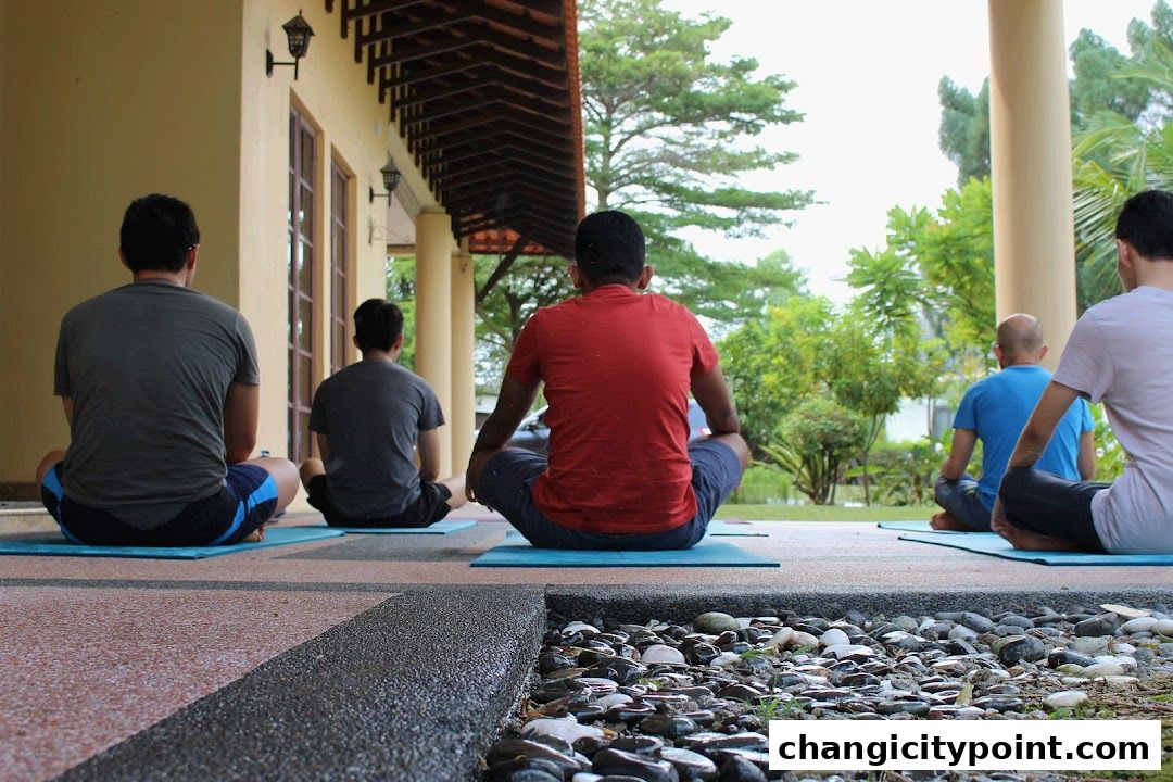 People meditating outdoors on yoga mats in front of a building.