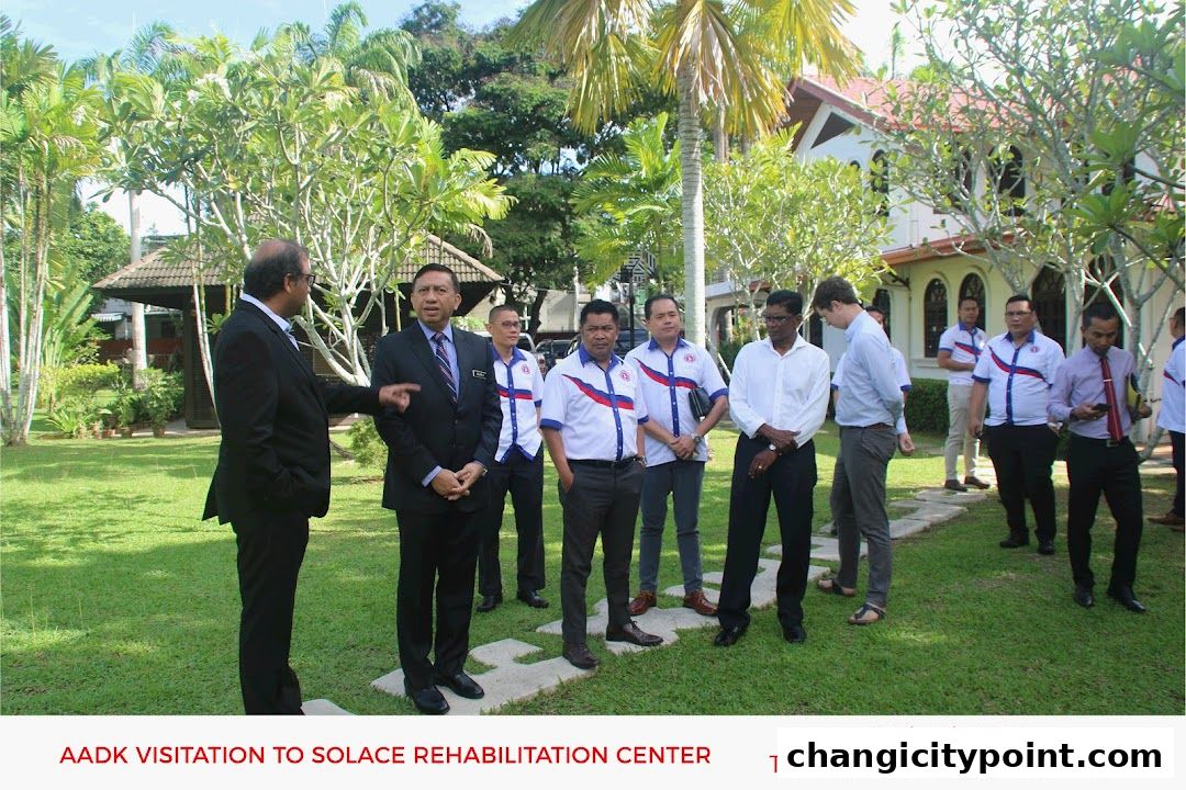 A group of men in formal and casual attire stand on a lawn outside a building.