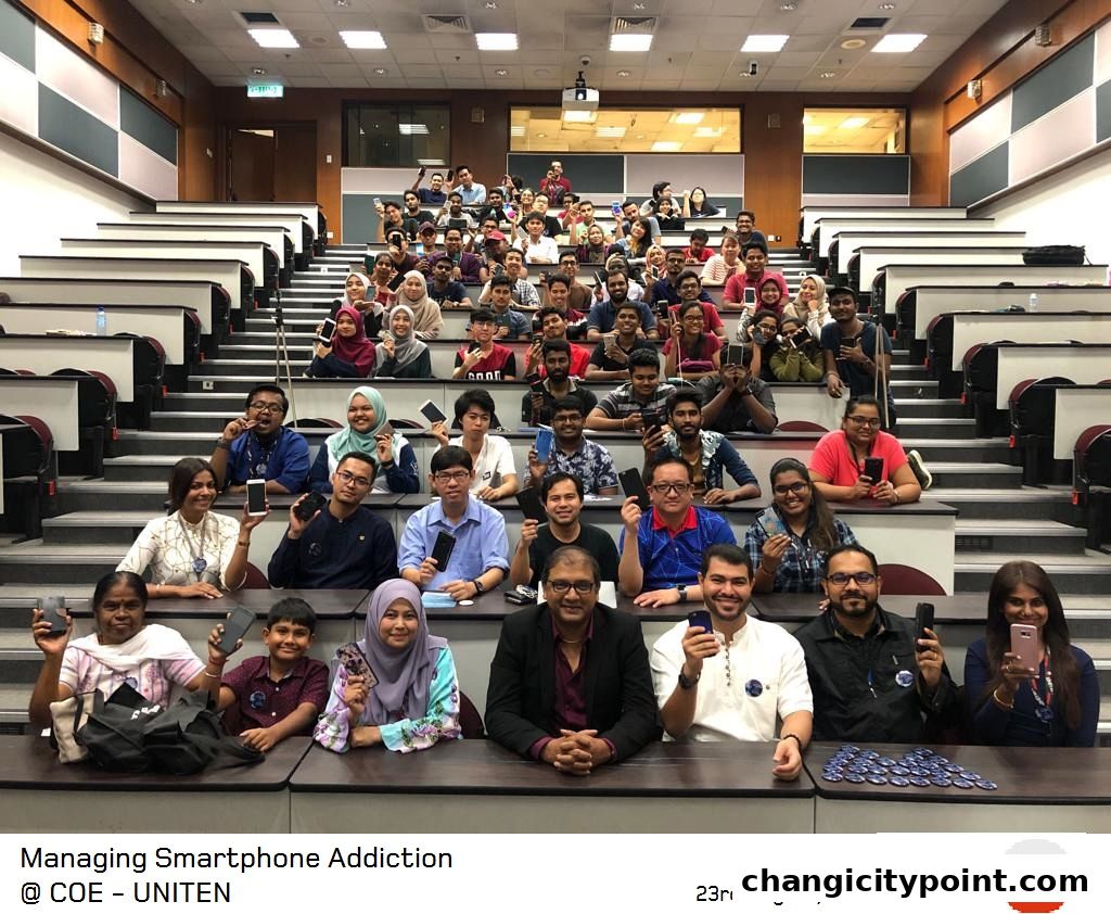 A group of people in a lecture hall holding up smartphones.