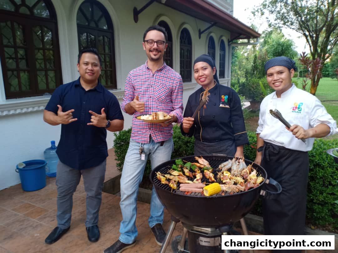 Four people stand around a barbecue grill with food cooking.