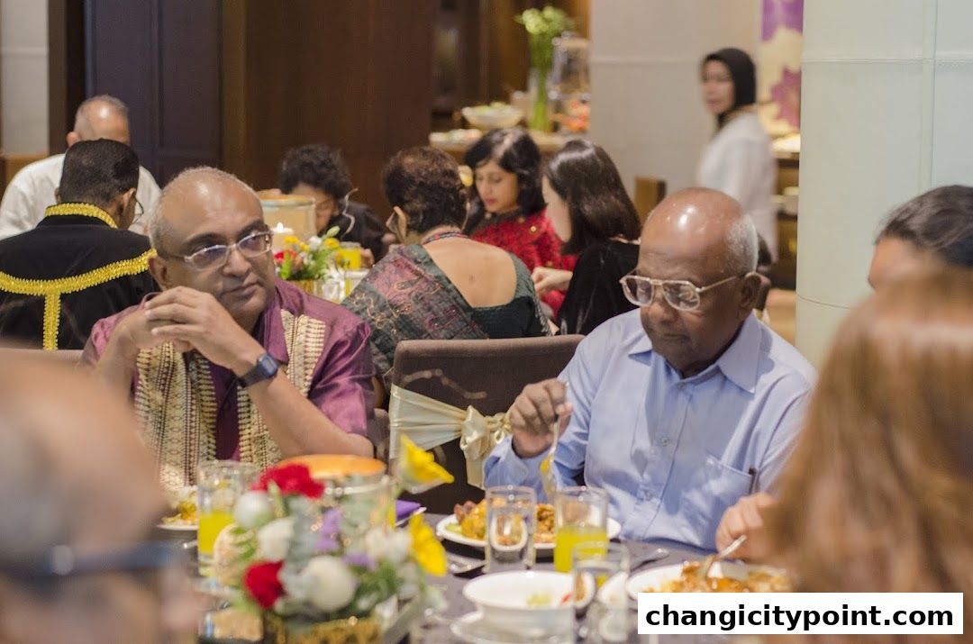 People dining at a formal event with floral centerpieces and food on tables.