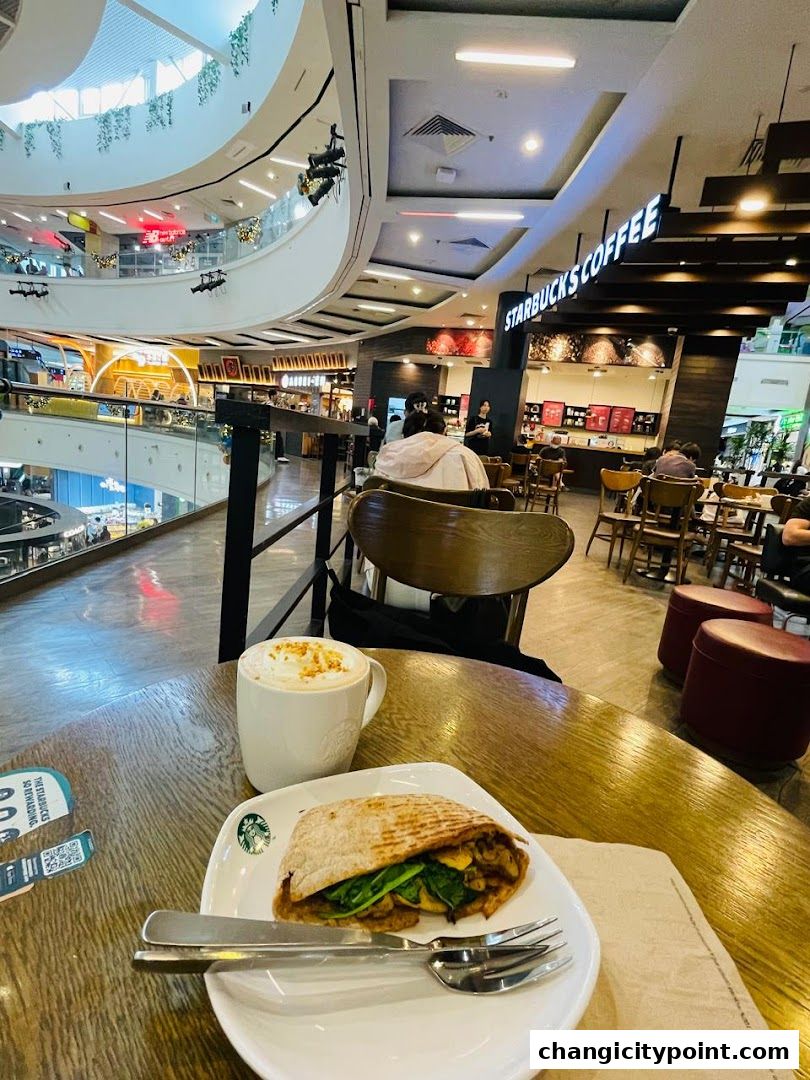 A table at Starbucks with a coffee and a sandwich, overlooking a mall atrium.