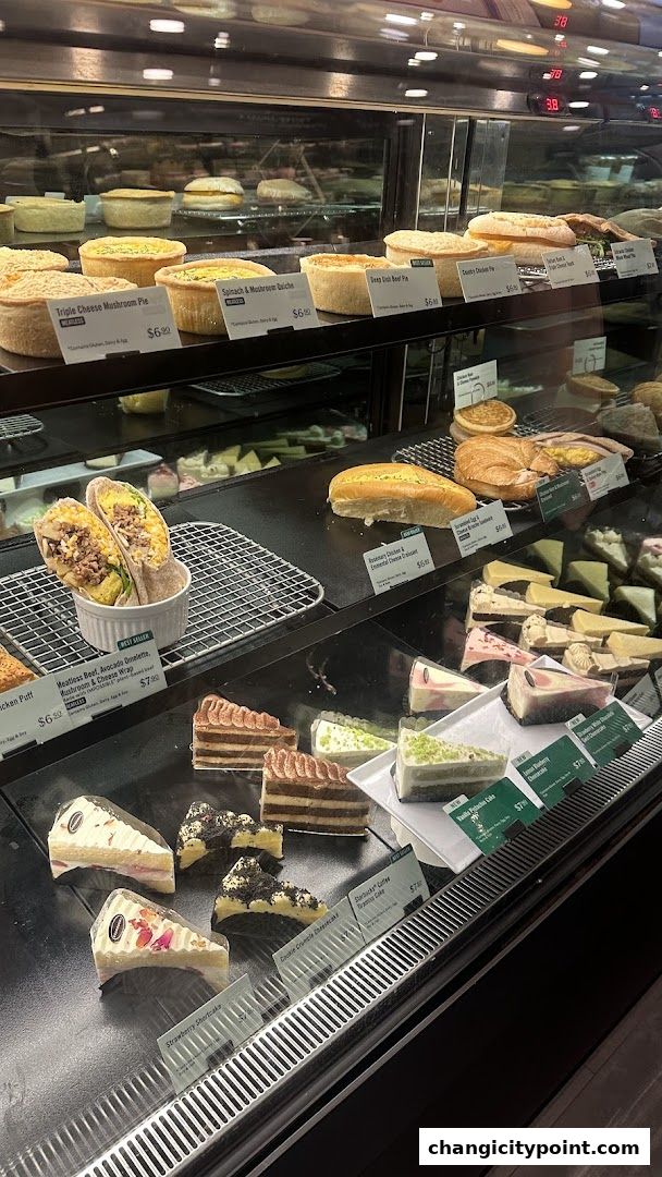 A display case filled with various pies, wraps, sandwiches, and cakes.