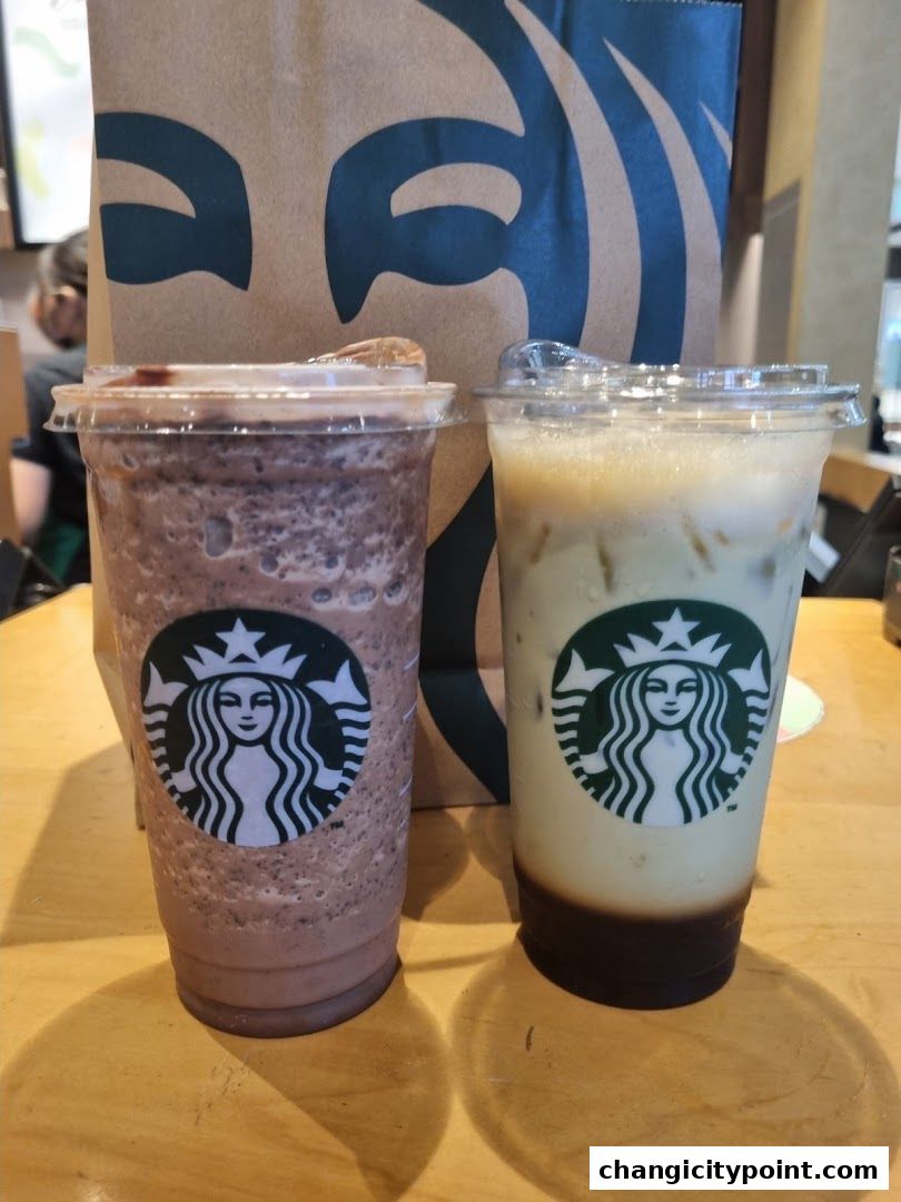 Two Starbucks drinks and a shopping bag on a wooden table.