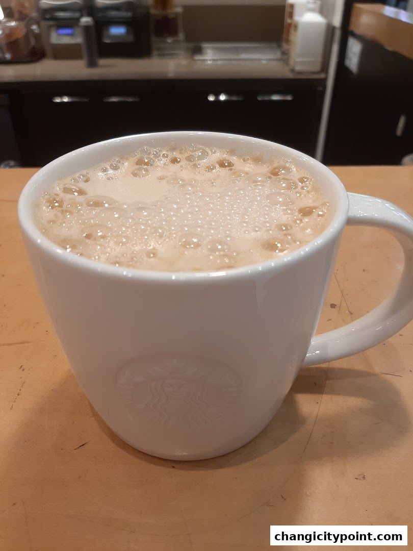 A white mug with the Starbucks logo filled with a frothy beverage.