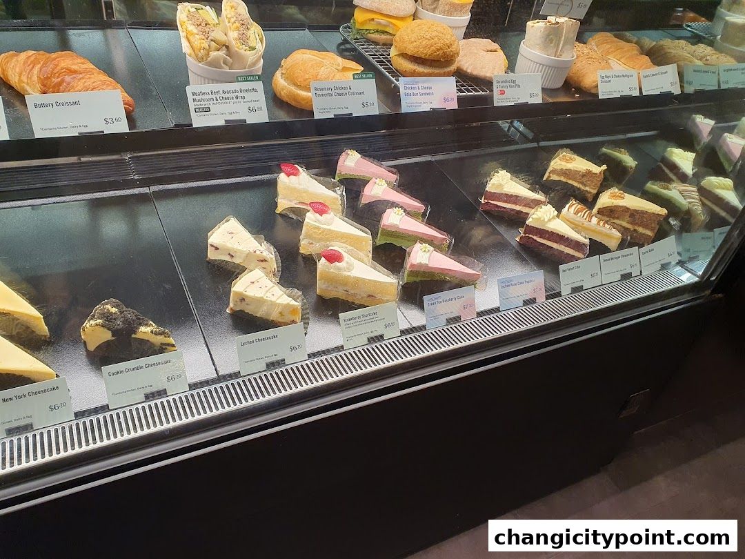 A display case filled with various pastries, cakes, and sandwiches at Starbucks.
