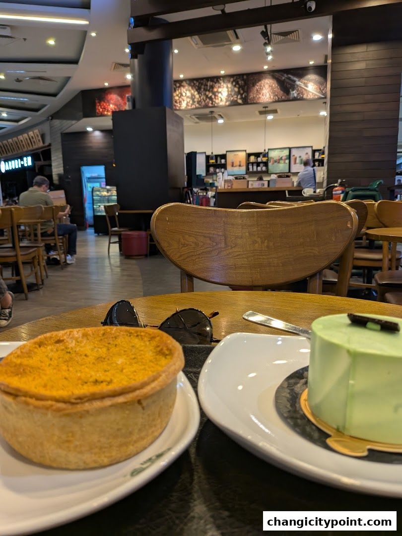 A table at Starbucks with a savory tart and a green cake, with the cafe interior in the background.