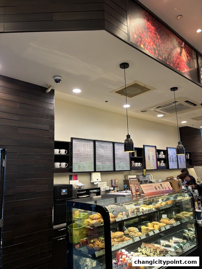 Interior view of a Starbucks coffee shop with a display case of pastries and a menu board.