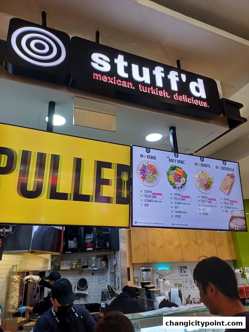 A digital menu board displays options for kebabs, bowls, burritos, and quesadillas at Stuff'd.