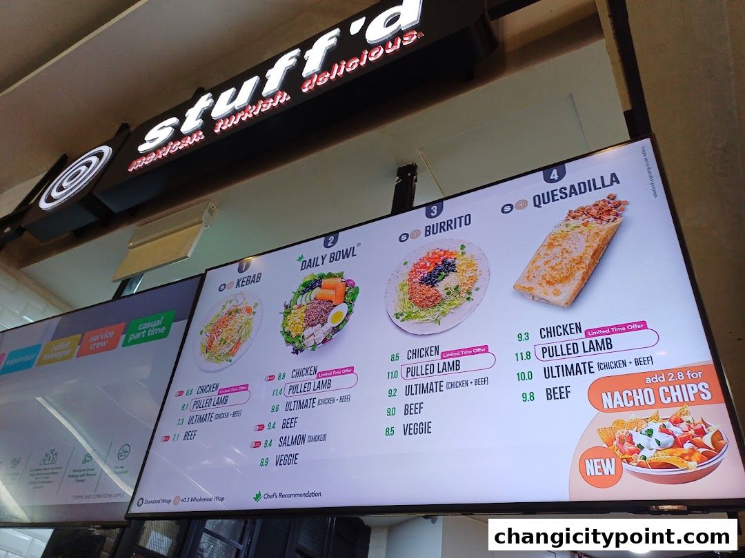 A digital menu board displaying various food items like kebabs, bowls, burritos, and quesadillas.