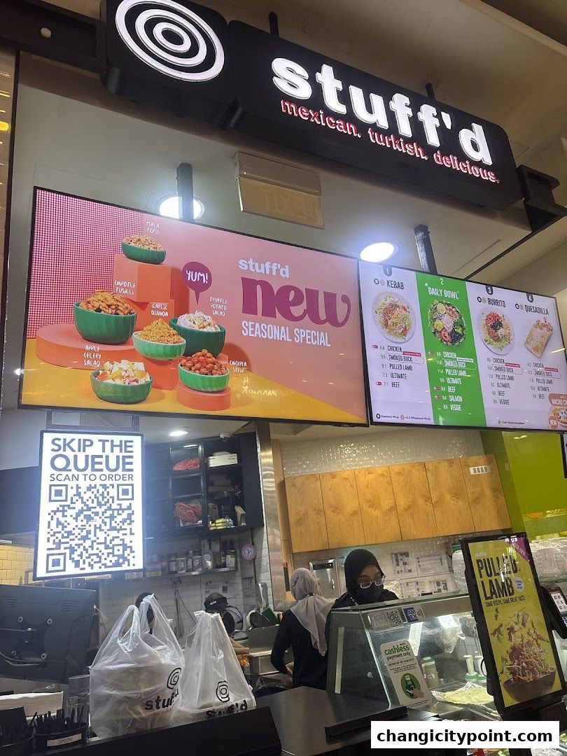 A food stall with a menu board displaying various dishes and a QR code for ordering.